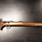 Ylhäältä otettu kuva kivääristä tummaa taustaa vasten.